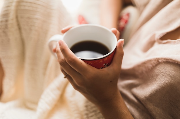 Eine obenliegende Ansicht eines Mädchens, das Kaffeetasse in den Händen hält