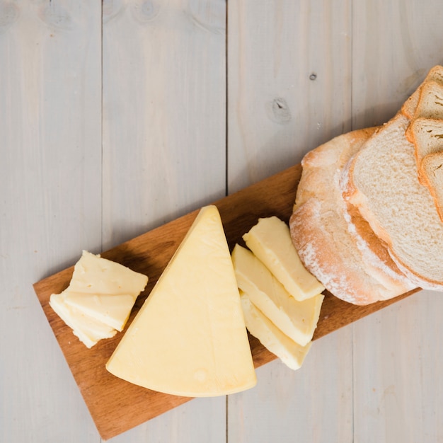 Eine obenliegende Ansicht von Brotscheiben mit Käse zwängt auf hackendem Brett über Holztisch