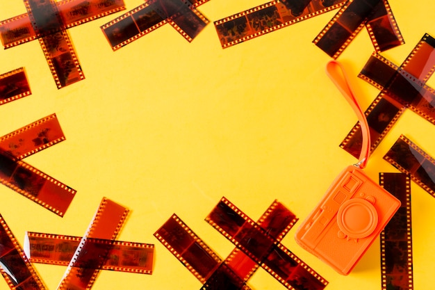 Eine obenliegende Ansicht von Filmstreifen mit orange Geldbeutel auf gelbem Hintergrund