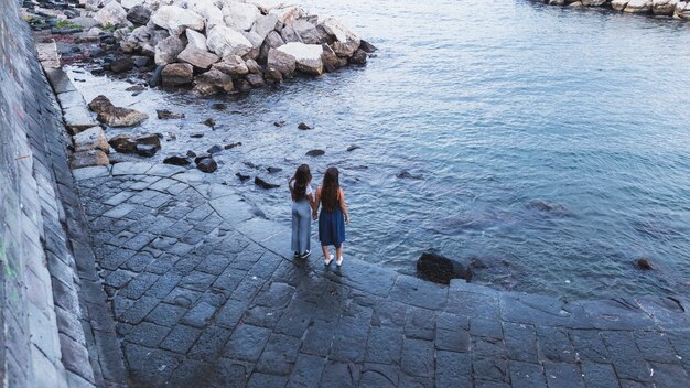 Eine obenliegende Ansicht von zwei jungen Frauen, die nahe der Küste stehen