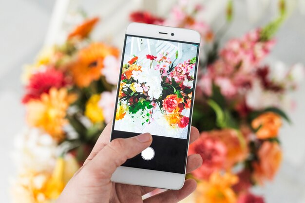 Eine Person, die Foto des Blumenblumenstraußes mit Smartphone macht