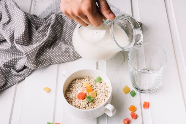 Eine Person gießt Milch in das Glas mit Haferflocken