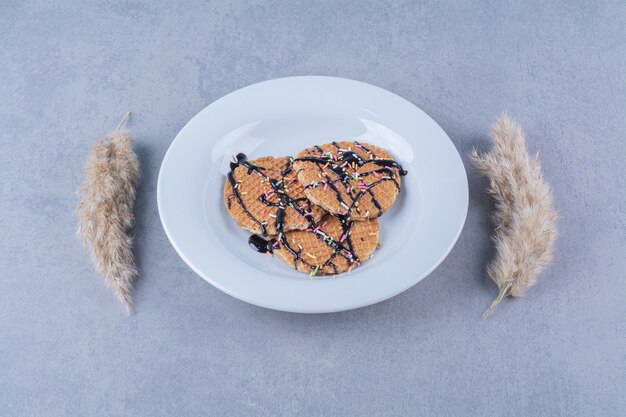 Eine Pfanne mit runder, rötlicher Waffel mit Streuseln und Sahne.