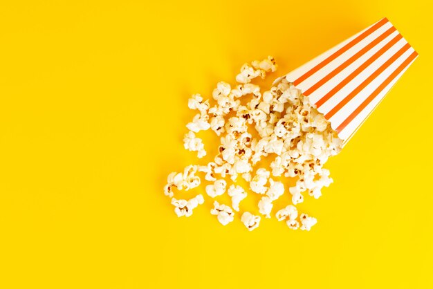 Eine Popcorn-Packung mit Draufsicht gesalzen und lecker auf dem gelben Hintergrund verteilt