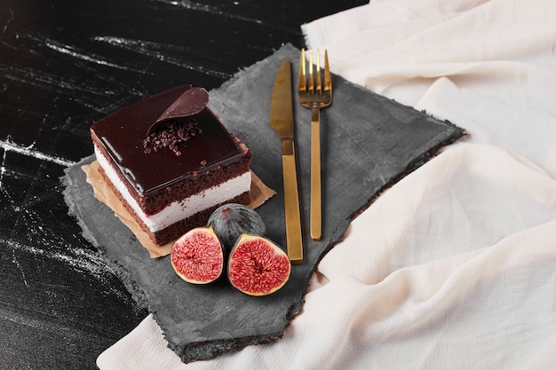 Eine quadratische Scheibe Schokoladenkäsekuchen auf einer Steinplatte.