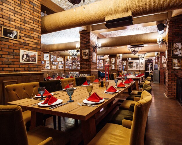 Eine Restauranthalle mit Holztischen und Rohren aus rotem Backstein an der Decke