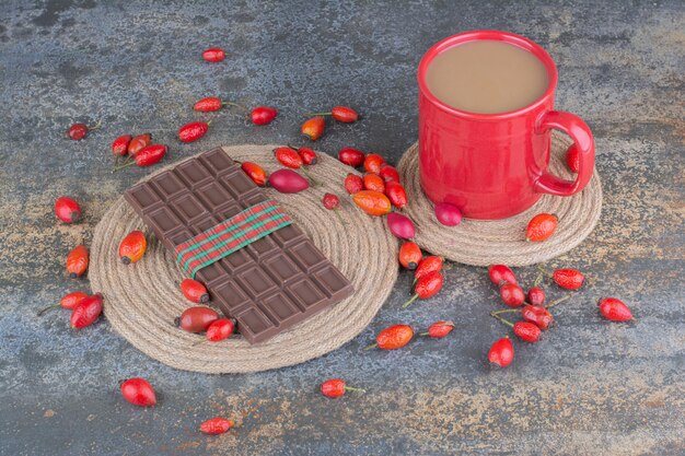 Eine rote Tasse Getränk mit Schokolade und Hagebutten auf Marmorhintergrund. Foto in hoher Qualität