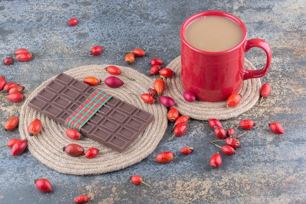 Eine rote Tasse Getränk mit Schokolade und Hagebutten auf Marmorhintergrund. Foto in hoher Qualität