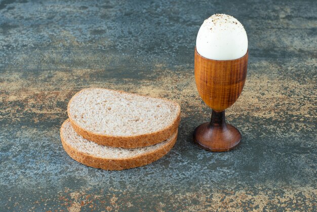 Eine Scheibe Brot mit gekochtem auf Marmorhintergrund