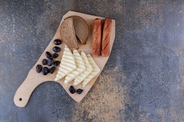 Eine Scheibe Brot serviert mit Wurst und Käse auf einem Holzbrett