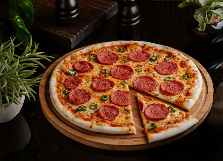 Kostenlose Foto eine scheibe geschnitten von der klassischen pepperonipizza mit rollen des grünen paprikas