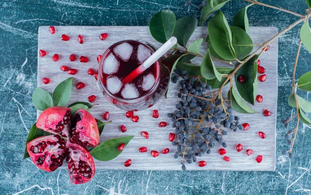 Eine Scheibe Granatapfel und Saft auf dem Brett, auf dem blauen Hintergrund. Hochwertiges Foto