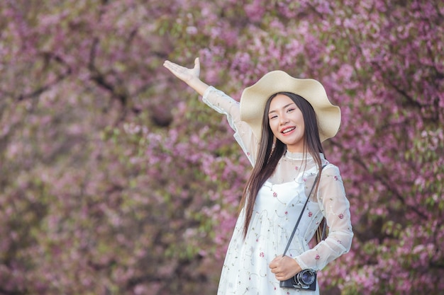 Eine schöne Frau macht ein Foto mit einer Filmkamera im Sakura-Blumengarten.