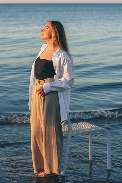 Eine schöne Frau steht bei Sonnenuntergang am Meer