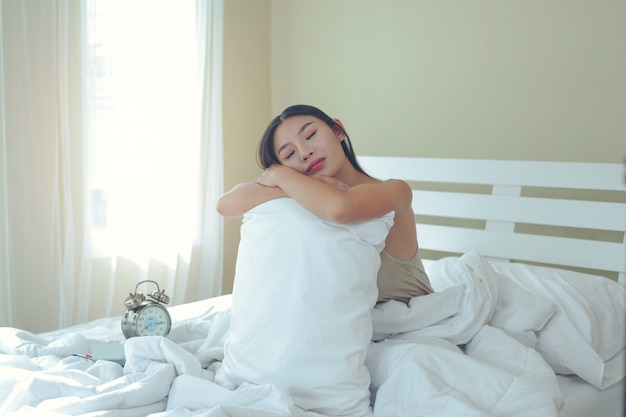 Eine schöne junge Frau schläft und ein Wecker im Schlafzimmer zu Hause.