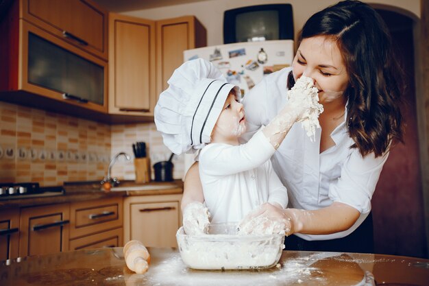 Eine schöne junge Mutter mit ihrer kleinen Tochter kocht in der Küche zu Hause