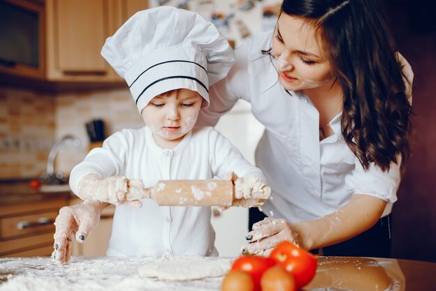 Eine schöne junge Mutter mit ihrer kleinen Tochter kocht in der Küche zu Hause