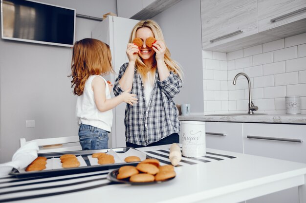 Eine schöne junge Mutter mit ihrer kleinen Tochter kocht in der Küche zu Hause