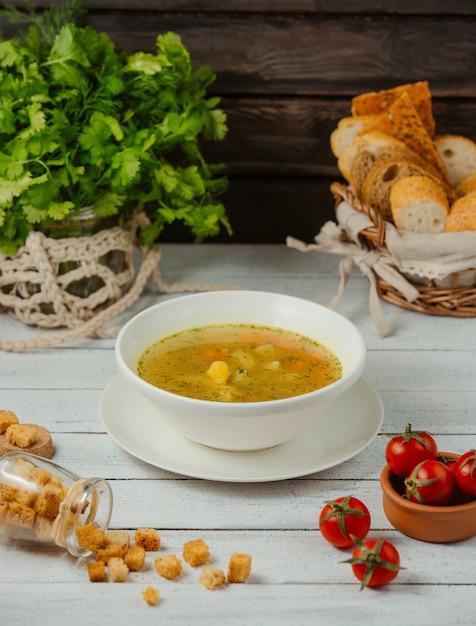 eine Schüssel Hühnersuppe mit Kartoffeln, Karotten und Dill, serviert mit Brotscheiben