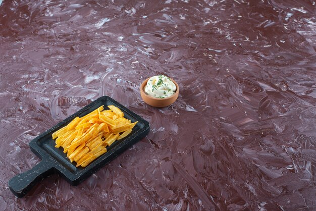 Eine Schüssel Joghurt und Pommes Frites in einem Brett auf dem Marmortisch.