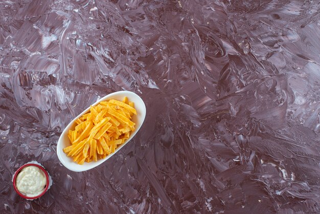 Eine Schüssel Joghurt und Pommes Frites in einer Schüssel auf dem Marmortisch.