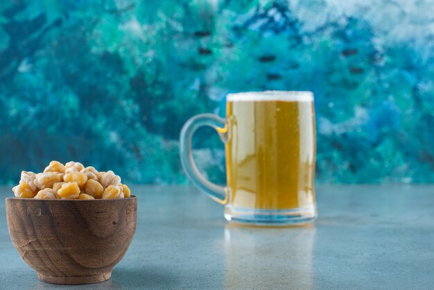 Eine Schüssel Kichererbsen und ein Glas Bier auf dem Marmortisch.