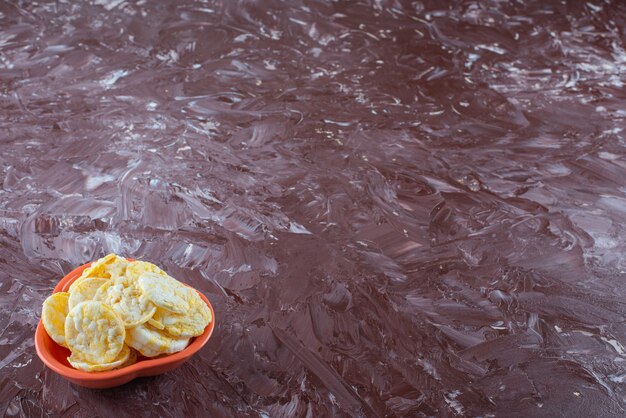 Eine Schüssel mit leckeren Käsechips auf dem Marmortisch.