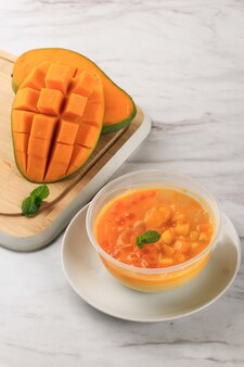 Eine schüssel mit mango-sago, beliebtes dessert aus mangosaft, gelee, sagoperle, kondensmilch und gesüßter kondensmilch