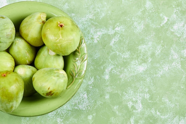 Kostenloses Foto eine schüssel mit saftigen grünen feigen auf grün.