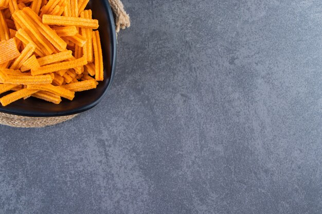 Eine Schüssel mit Süßkartoffelpommes auf einem Untersetzer auf der Marmoroberfläche