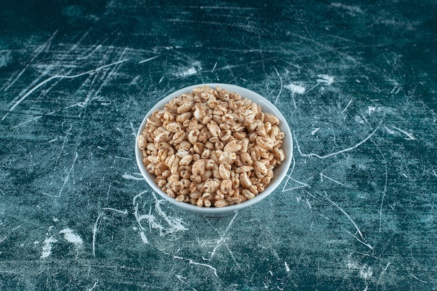 Kostenloses Foto eine schüssel mit trockenen cornflakes auf blauem hintergrund. foto in hoher qualität