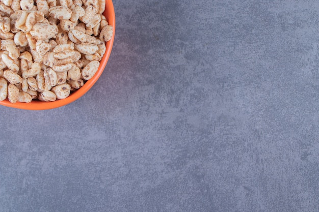 Eine Schüssel mit trockenen Cornflakes auf blauem Hintergrund.