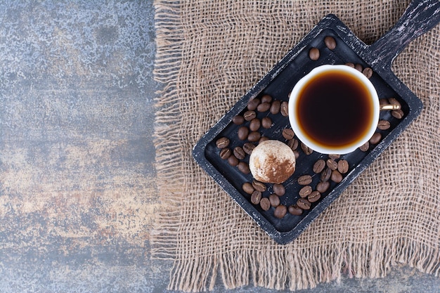 Eine Tasse Aromakaffee mit Kaffeebohnen auf dunklem Brett