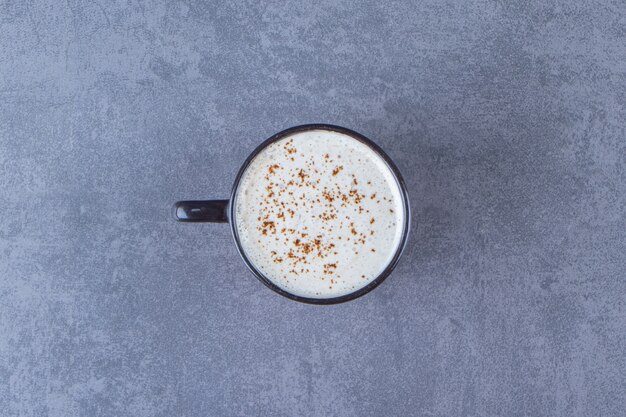 Eine Tasse Cappuccino mit Milch auf dem blauen Tisch.