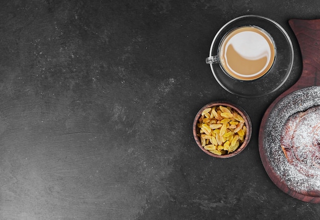 Eine Tasse Cappuccino mit trockenen Früchten und süßem Brötchen.