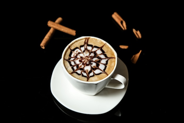 Eine tasse cappuccino und zimtstangen auf der tischansicht Kostenlose Fotos