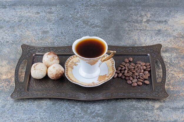 Eine Tasse dunklen Kaffee mit Keks auf dunklem Brett. Foto in hoher Qualität