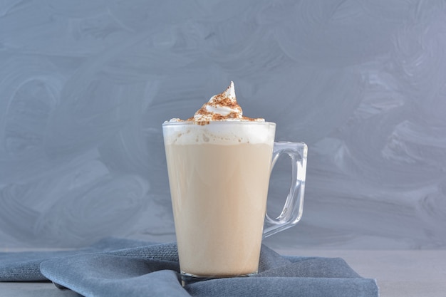 Kostenloses Foto eine tasse heißen köstlichen kaffees verziert mit kakao auf blauem tuch.