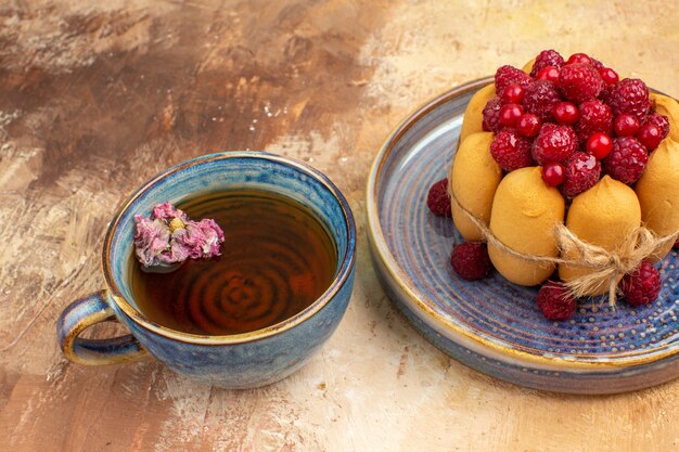 Eine Tasse heißen Kräutertee weichen Kuchen mit Früchten auf gemischten Farbtisch