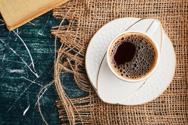 Eine Tasse Kaffee auf einem Stück Sackleinen.