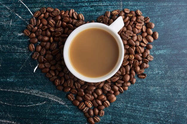 Eine Tasse Kaffee auf Körnern in Herzform.