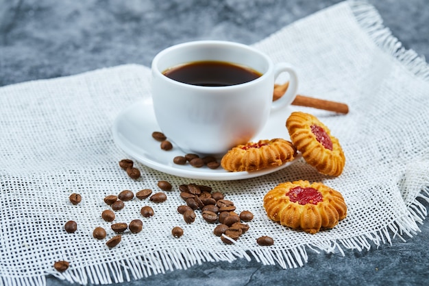 Eine Tasse Kaffee, Kekse, Kaffeebohnen und Zimt.