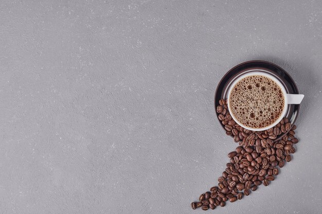 Eine Tasse Kaffee mit Arabica-Bohnen herum.