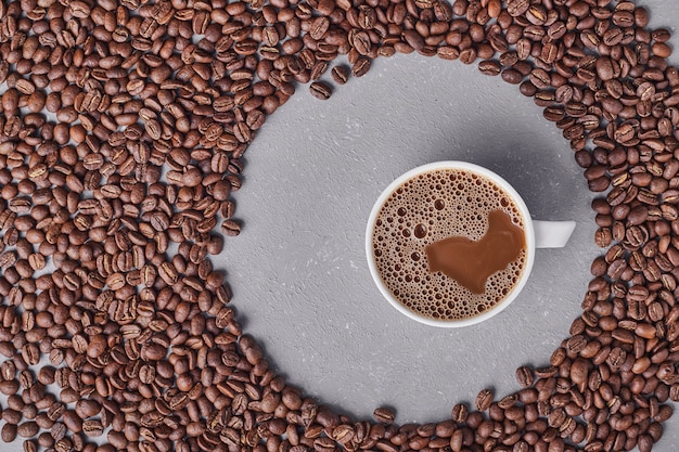 Eine Tasse Kaffee mit Arabica-Bohnen herum.