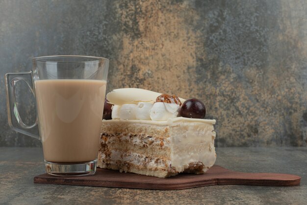 Eine Tasse Kaffee mit einem Stück Kuchen auf Holzbrett.