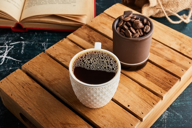 Eine Tasse Kaffee mit Schaum und Körnern beiseite.