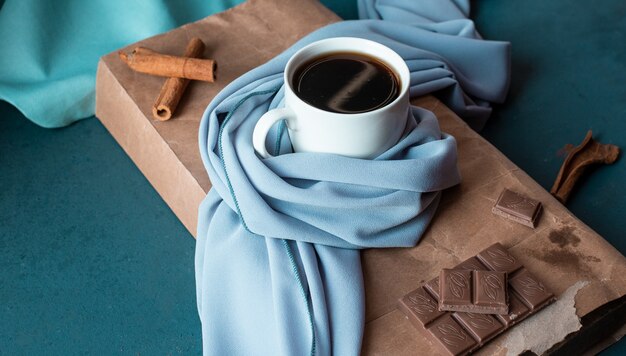 Eine Tasse Kaffee mit Zimtstangen und Schokoriegel.