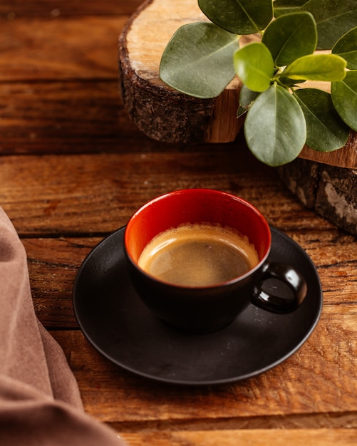 Eine Tasse Kaffee von oben, die in der schwarzen Tasse auf dem braunen Holztisch halb leer ist, trinkt Kaffeeflüssigkeit