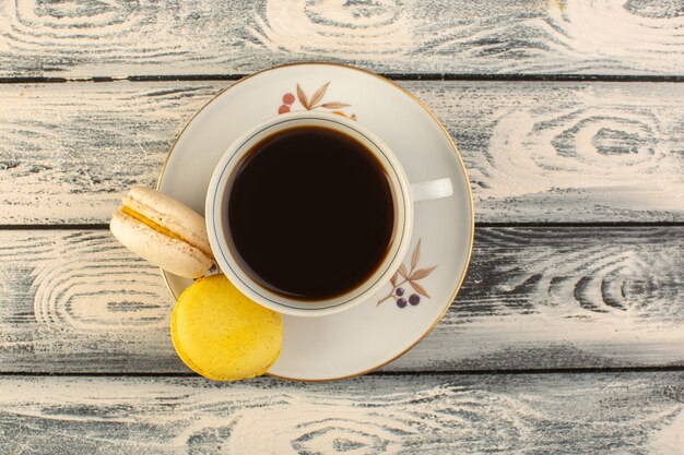 Eine Tasse Kaffee von oben heiß und stark mit französischen Macarons auf dem grauen rustikalen Schreibtischkaffee-Heißgetränk