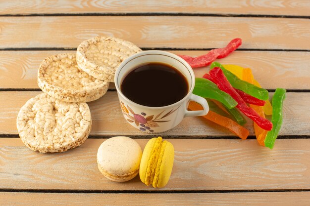 Eine Tasse Kaffee von oben heiß und stark mit französischen Macarons und Marmelade auf dem cremefarbenen rustikalen Schreibtisch trinken Kaffee Foto stark